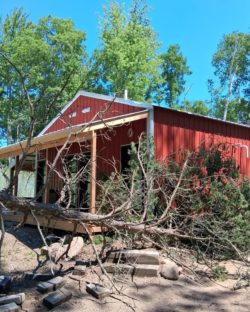 Red cabin with white trim surrounded by trees at Cuyuna Crossing